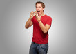 portrait of young man eating pizza over grey background
