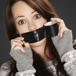 portrait of scared girl being silenced by herself over black bac