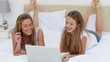 Video: Happy women lying while looking at a laptop Happy women lying while looking at a laptop