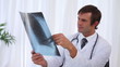 Doctor examining a chest x-ray and then looking at camera