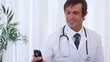 Smiling doctor sending a text message