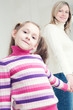 Little girl holding her mother by the hand and looking at camera