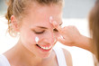 Daughter applying cream on mother's face