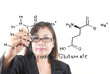 Teacher lady writing scientific formula on the whiteboard.