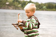 Boy holding twig by river, side view