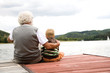 Grandfather sitting with grandson on pier