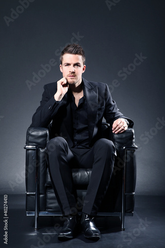 Foto: Junger sportlicher Mann sitzt auf Sessel Junger sportlicher Mann sitzt auf Sessel