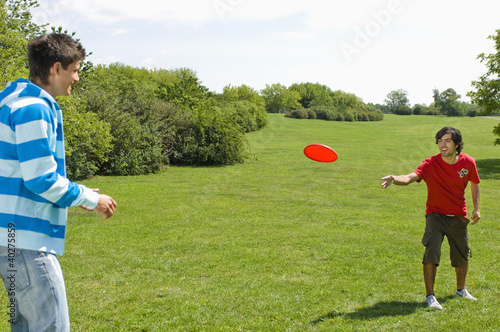 Photo: Friends playing with plastic disc on park Friends playing with plastic disc on park