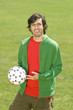 Young man holding soccer ball in park, portrait