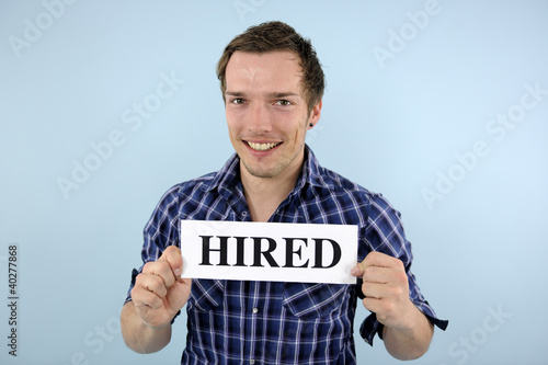 Photo: young man holding hired sign young man holding hired sign