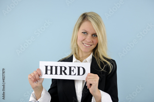 Photo: young busineswoman holding hired sign young busineswoman holding hired sign