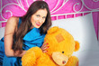 beautiful young woman on a bed with teddy bear
