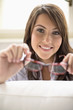 Young woman holding spectacles, smiling, portrait