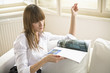 Young woman holding magazine while sitting on sofa