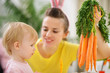 Mother showing baby bunch of carrots