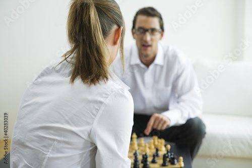 Photo: Mid adult couple playing chess Mid adult couple playing chess