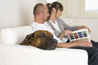 Couple sitting on sofa, looking at catalog, side view