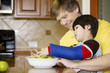 Foto: Father helping disabled son with work in the kitchen Father helping disabled son with work in the kitchen