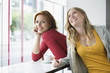 Young women leaning on window sill, smiling
