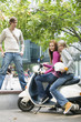 Young women sitting on motor scooter, smiling, portrait