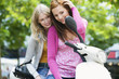 Young women sitting on motor scooter, smiling