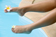 female foot with a flower over blue water....
