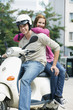 Young couple sitting on motor scooter, smiling