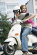 Young couple sitting on motor scooter, smiling