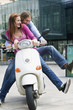 Young couples sitting on motor scooter, smiling
