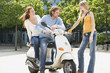 Young couple on motor scooter, talking to friend