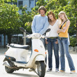 Friends looking at motor scooter, smiling