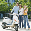 Friends looking at motor scooter, smiling