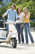 Friends looking at motor scooter, smiling
