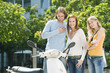 Friends looking at motor scooter, smiling