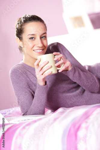 Photo: woman holding a cup of coffee in bed woman holding a cup of coffee in bed