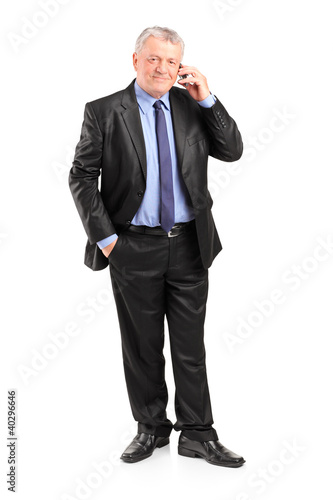 Photo: Full length portrait of a mature businessman talking on a phone Full length portrait of a mature businessman talking on a phone