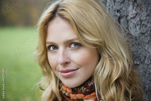 Photo: Young woman leaning by tree trunk, portrait, close-up Young woman leaning by tree trunk, portrait, close-up