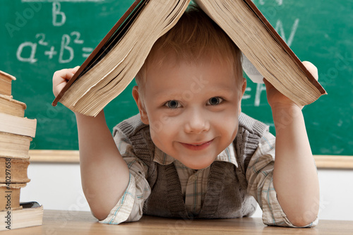 Photo: Cheerful smiling little boy sitting at the table. Cheerful smiling little boy sitting at the table.