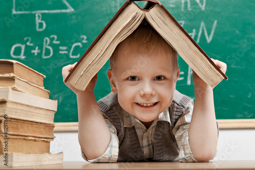 Foto: Cheerful smiling little boy sitting at the table. Cheerful smiling little boy sitting at the table.