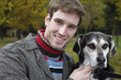 Young man with dog, smiling, portrait
