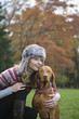 Photo: Young woman smiling with dog in garden, looking away Young woman smiling with dog in garden, looking away