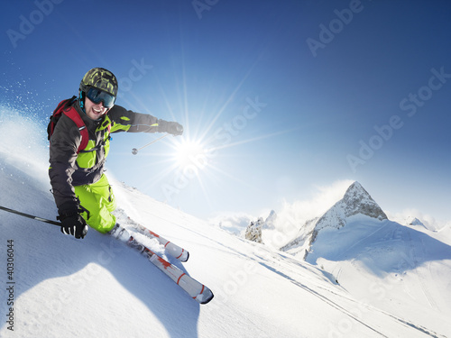 Photo: Skier in mountains, prepared piste and sunny day Skier in mountains, prepared piste and sunny day