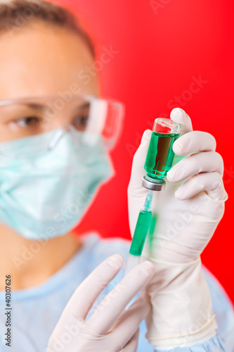 Photo: Young woman doctor preparing injection with ampoule and syringe Young woman doctor preparing injection with ampoule and syringe