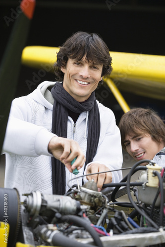 Photo: Young man screwing in airplane engine Young man screwing in airplane engine
