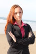 Redhead woman standing with hands folded , at the beach