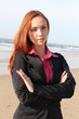 Redhead woman standing with hands folded , at the beach