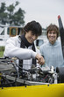 Young man screwing in airplane engine, smiling