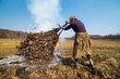 Senior rural woman burning fallen leaves