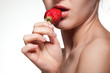Young woman biting strawberry isolated on white