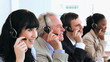 Joyful call centre agents sitting while wearing headsets
